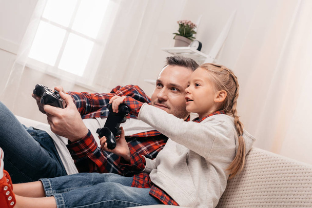 father and daughter playing with joysticks - 写真・画像