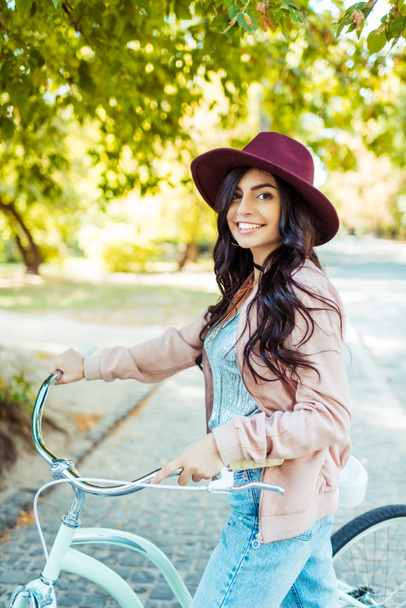 femme en chapeau debout avec vélo
  - Photo, image