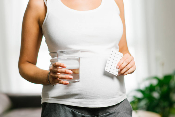 Pregnant woman holding folic acid blister and glass of water - Fotoğraf, Görsel