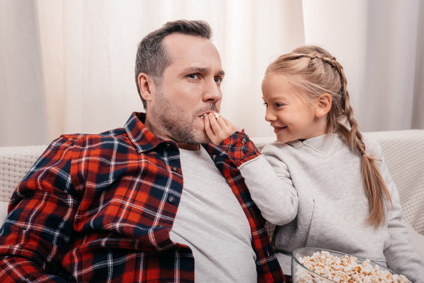 father and daughter eating popcorn - Фото, изображение