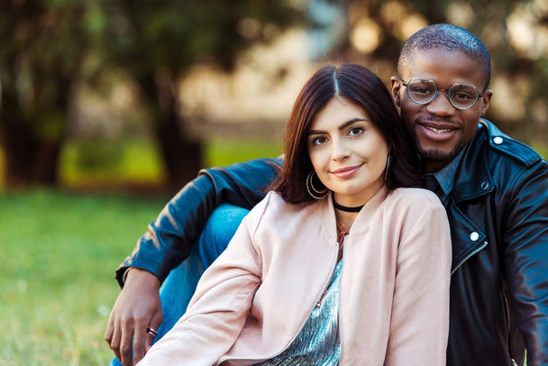 multicultural couple sitting on grass   - Photo, Image