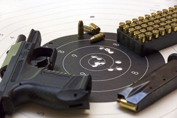 Gun and ammunition over bullseye score - Photo, Image