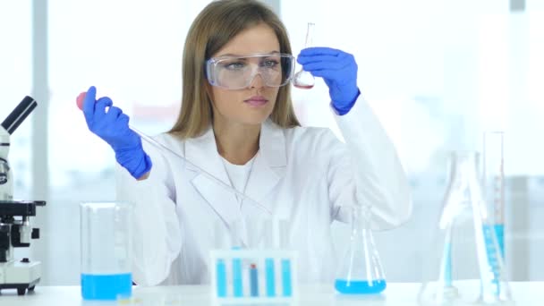 Científica femenina ocupada investigando y reaccionando en laboratorio
 - Imágenes, Vídeo