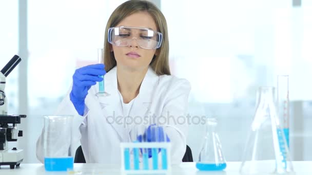 Científica femenina trabajando en laboratorio, vertiendo solución en tubo de ensayo
 - Imágenes, Vídeo