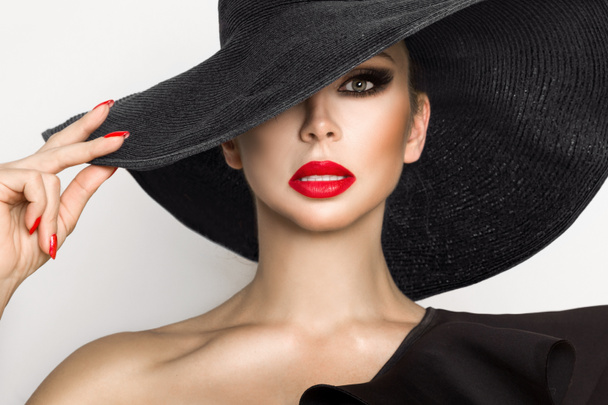 Retrato de una mujer elegante con sombrero y labios rojos sobre un fondo blanco
 - Foto, Imagen