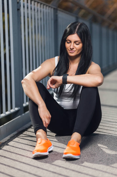 City workout. Beautiful woman with a smartwatch training in an urban setting - Φωτογραφία, εικόνα