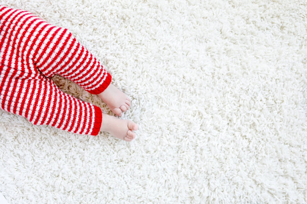 Close-up of baby body and legs in red Santa Clause trousers on Christmas - Foto, afbeelding