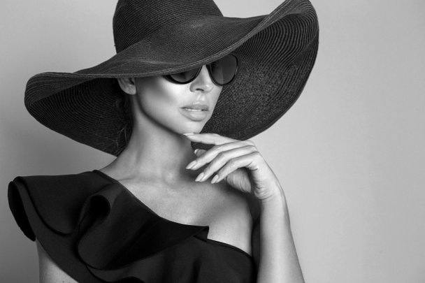 Portréja egy elegáns nő egy kalapot és napszemüveget, egy bézs háttérrel - Fotó, kép