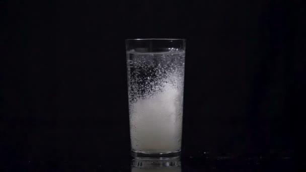 Effervescent tablet falling in full glass of water - Footage, Video
