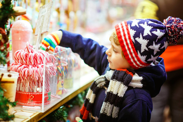 Piccolo ragazzo carino comprare dolci da uno stand cancy sul mercato di Natale
 - Foto, immagini