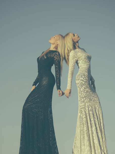 Two girls with long blond hair posing on grey sky - Foto, Imagem