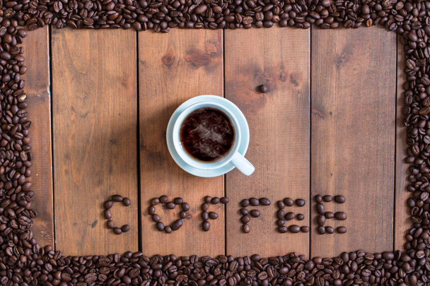 Bovenaanzicht kopje koffie met koffiebonen vierkante frame op houten  - Foto, afbeelding