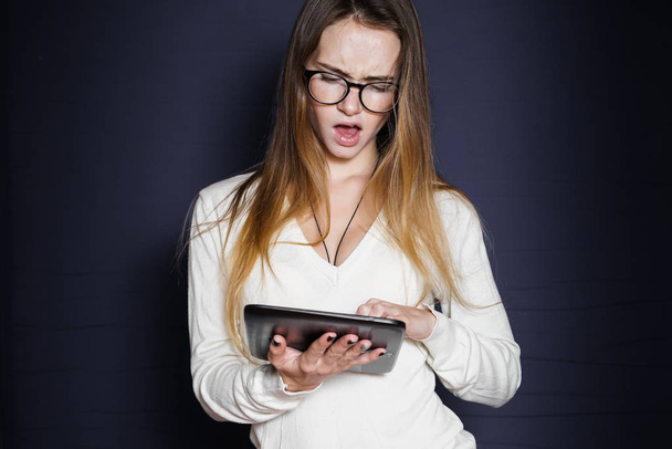 girl in glasses grieves typing something in her tablet - Zdjęcie, obraz