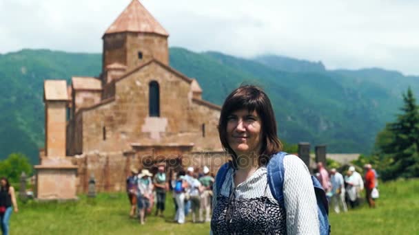 Mujer turista sonriente frente a la antigua iglesia armenia en verano
 - Metraje, vídeo