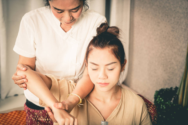 Las mujeres está recibiendo masaje de hombro y codo en el spa de masaje tailandés
 - Foto, imagen