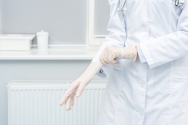 Ärztin zieht Handschuhe an - Foto, Bild