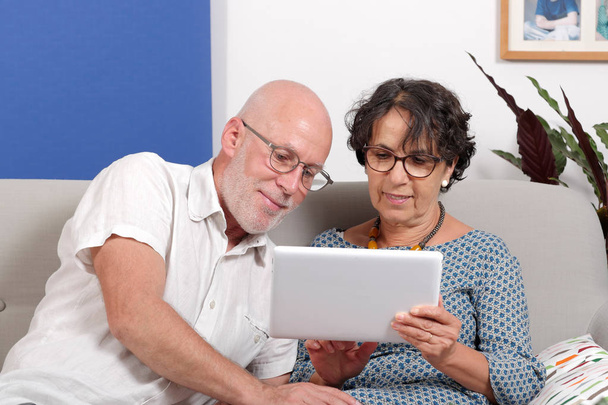  пожилая пара с помощью планшета и улыбаясь
 - Фото, изображение