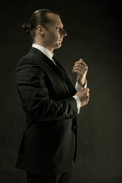 El hombre atractivo en traje negro sobre fondo oscuro
 - Foto, Imagen