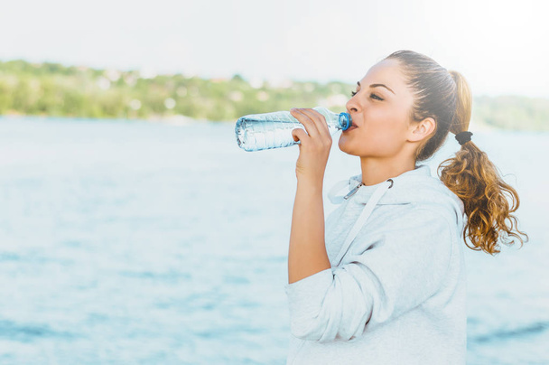 girl in sport clothes drinking water  - Photo, image