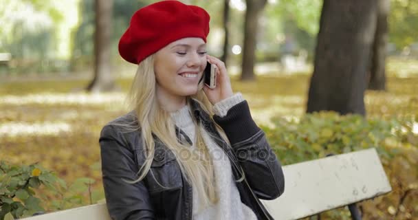Pretty woman in beret speaking on phone - Filmati, video