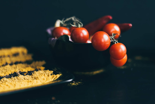 A black dish of delicious fresh tomatoes cherry lying on a wooden cutting board. Herbs are used as a decoration. - Fotoğraf, Görsel