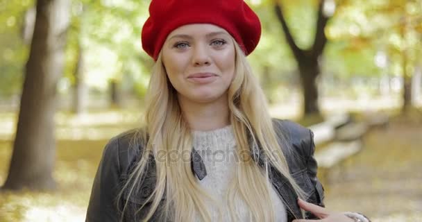 Woman in red beret walking in park - Materiał filmowy, wideo