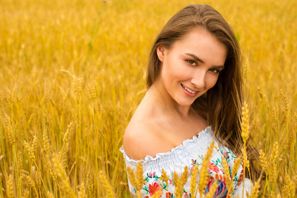 Young woman on a background of golden wheat field - 写真・画像
