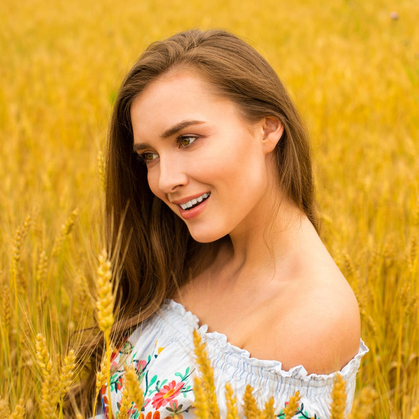 Jovem mulher em um fundo de campo de trigo dourado
 - Foto, Imagem