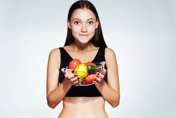 jovem menina bonita quer perder peso, mantém um prato com vegetais úteis e frutas nas mãos
 - Foto, Imagem