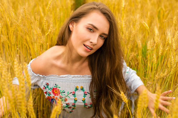 Young woman on a background of golden wheat field - Фото, зображення