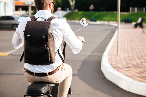 Cropped back view of man with backpack rides on motorbike - Foto, imagen