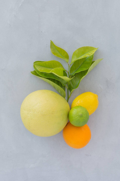 апельсини, лайм, лимон з зеленим листям на сірому тлі текстури вид зверху. натюрморт з цитрусами на темному тлі
. - Фото, зображення