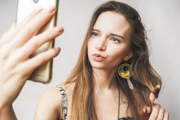 Happy smiling teen woman with mobile, looking something, doing selfie - Photo, image