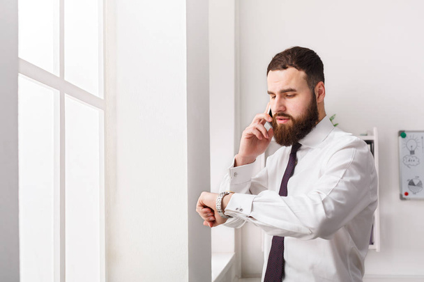 Serious businessman in formal wear has mobile phone talk in modern office - Foto, immagini