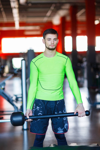 A young man is training in the gym with a hammer. - Foto, Bild