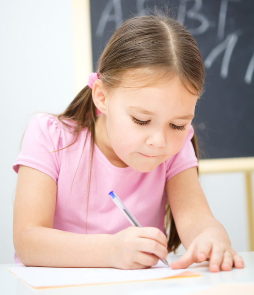 Little girl is writing using a pen - Photo, image