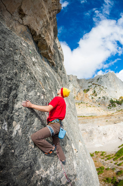 ein Bergsteiger mit Hut auf einem Felsen. - Foto, Bild