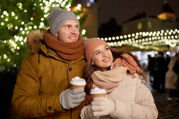happy young couple with coffee at christmas market - 写真・画像