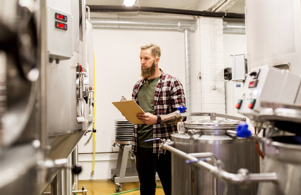 man with clipboard at craft brewery or beer plant - Фото, изображение