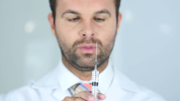 Injektion pidättäminen, lähikuva lääkäristä naamiossa Valmiina pistämään
 - Valokuva, kuva