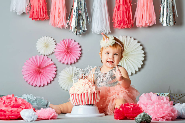Little baby girl eating birthday cake during cake smash party - Фото, изображение