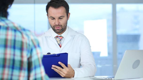 Doctor Writing Medical Reports of Patient, Sitting in Front - Photo, Image