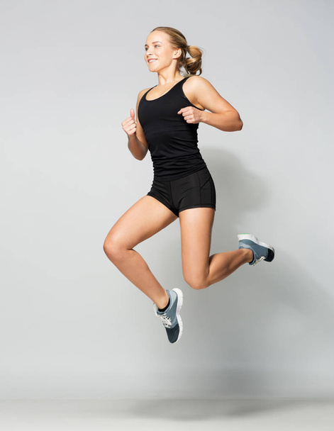 young woman in black sportswear jumping - Фото, изображение