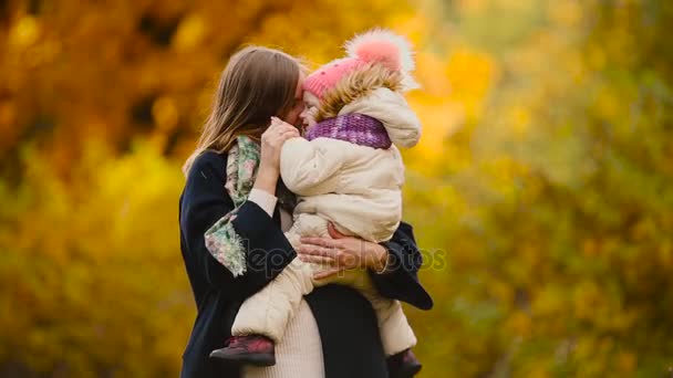 秋、黄色の母と娘のカエデの葉、遊んで笑って、笑って周りを離れるとき。ママは、抱擁し、秋に娘と遊ぶ。ボケ味と日光. - 映像、動画