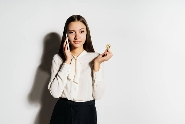 young successful modern business woman holding a gold bitcoin and talking on the phone - Φωτογραφία, εικόνα