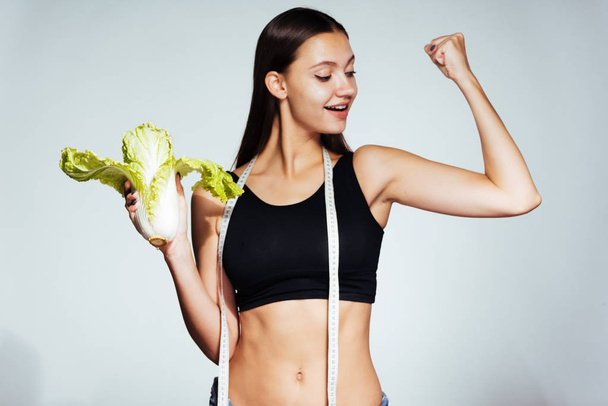 uma jovem atlética assiste sua figura, come um saudável repolho Pequim de baixa caloria
 - Foto, Imagem