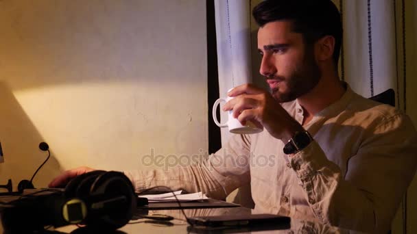Home worker sitting at desk using drinking coffee or tea - Felvétel, videó