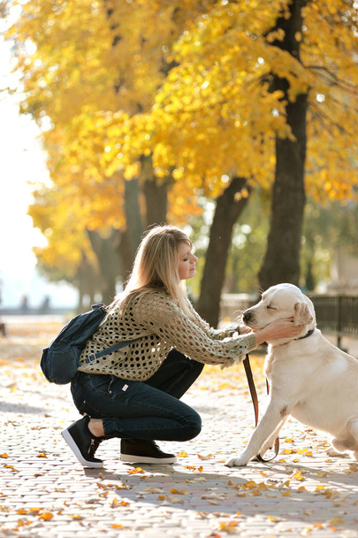 blondynka bawi się jej labrador w jesienny park - Zdjęcie, obraz