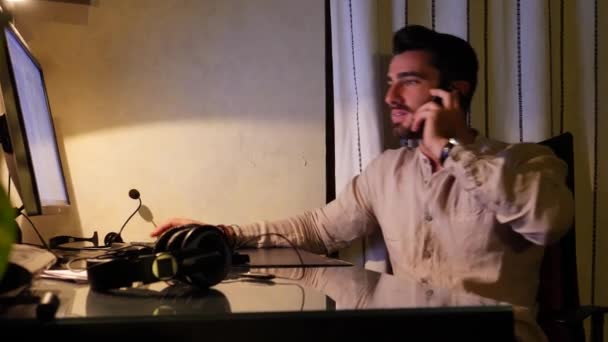 glücklicher Arbeiter, der zu Hause am Schreibtisch sitzt und am Telefon beschäftigt ist - Filmmaterial, Video