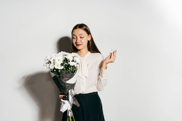 beautiful young happy girl celebrates something, holds a bouquet of white flowers in hands - Foto, imagen